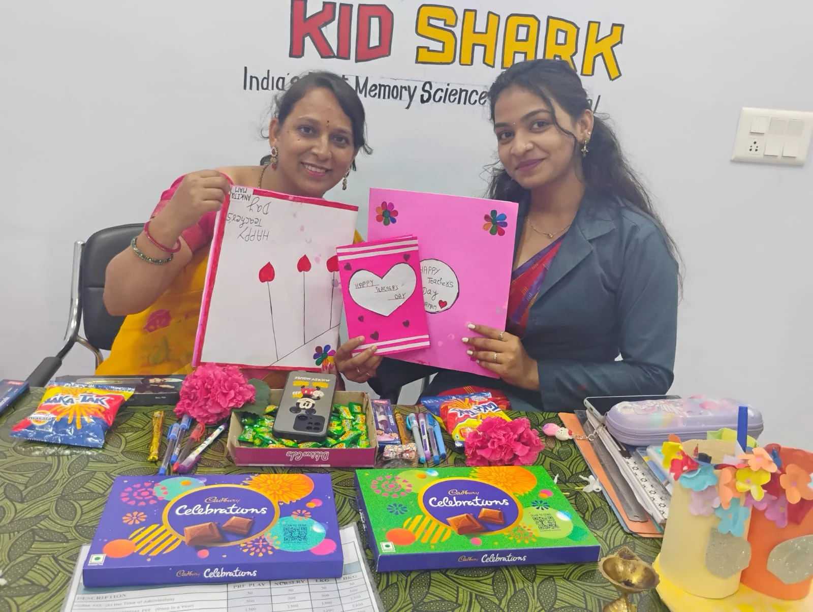 Two teachers holding colourful handmade artwork at Kid Shark